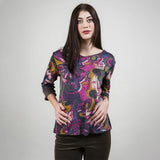 Woman wearing a colorful patterned top against a plain background