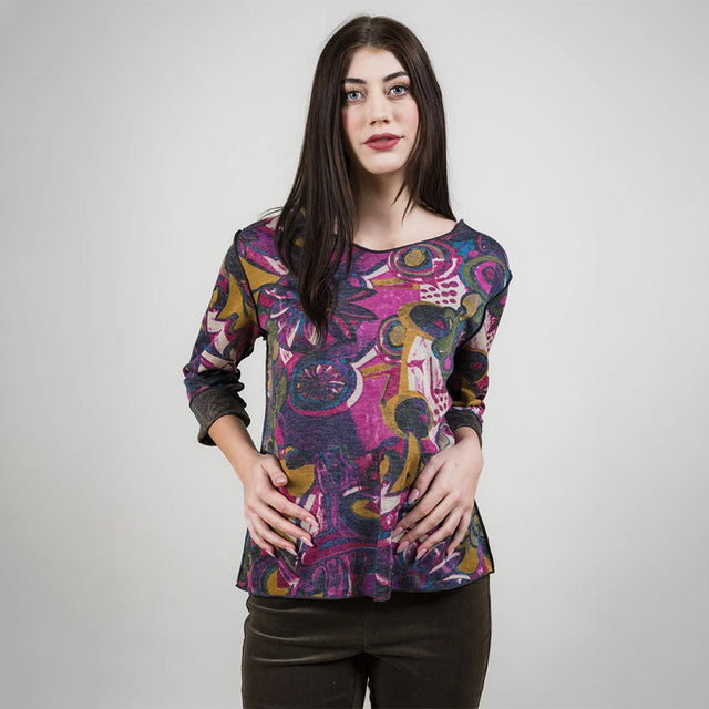 Woman wearing a colorful patterned top against a plain background