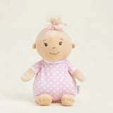 Stuffed toy baby doll with pink polka dot outfit on a light beige background