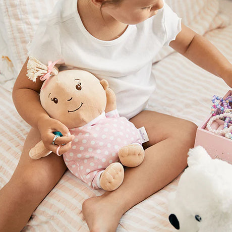 Child holding a plush toy with a smiling face on a soft surface