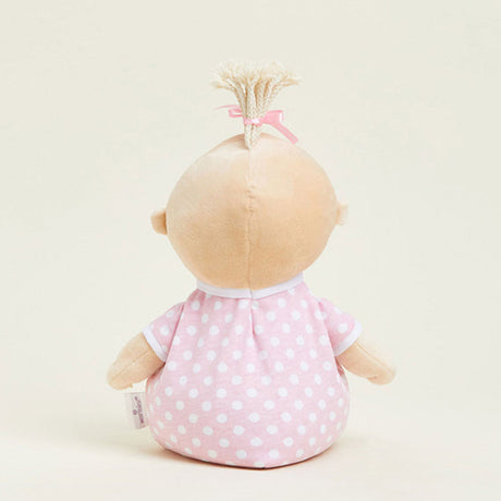 Stuffed doll with a pink polka dot dress on a beige background
