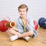 Child sitting on a wooden floor holding a football with colorful balls in the background