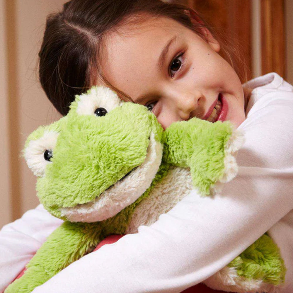 Child holding a green plush frog toy