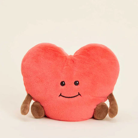 Heart-shaped plush toy with a smiley face on a beige background
