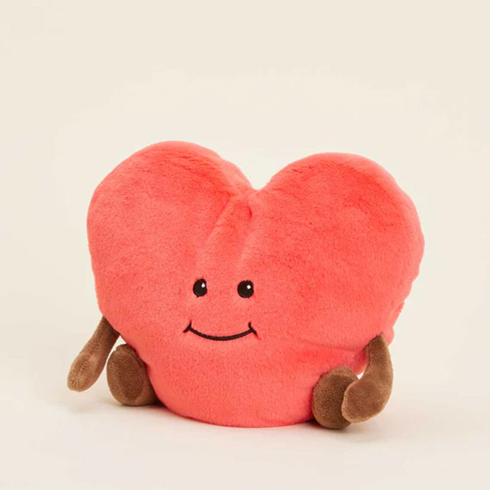 Plush heart-shaped toy with a smiley face on a beige background