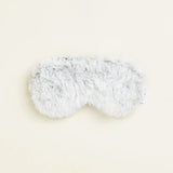 Fluffy white eye mask on a light beige background