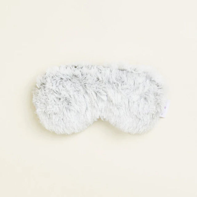 Fluffy white eye mask on a light beige background